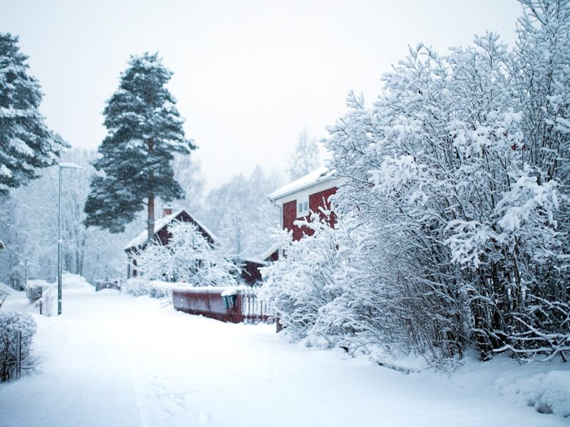 a snow covered road with a house in the distance